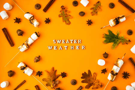 SWEATER WEATHER text. Cinnamon marshmallows leaves and anise on yellow background. Fall composition....