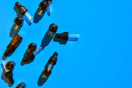 Bottles of essential oils on color background, flat lay. Cosmetic products. Dropper. Brown cosmetic...