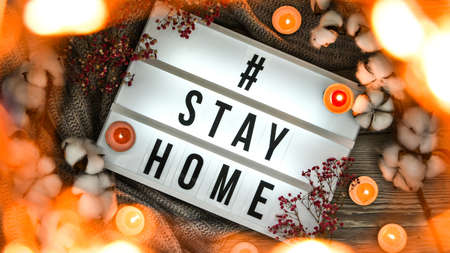 Hashtag Stay home. Text in your light box, with a background of sweater, candles, dried flower...