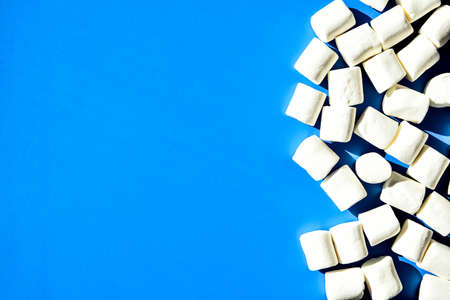 Marshmallows on blue background with Copy space. Flat lay. Top view. Background or texture of colorful mini marshmallows. Winter food background concept. Junk unheathy food.の写真素材