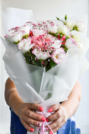 Beautiful woman hands hold bouquet of different flowers white and purple on white background. No people. Facelessの写真素材