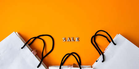 Wooden letters text SALE with packaging bags in front yellow background, copy space, banner Top view Flat lay seasonal sale, retail, shopping concept. Black friday saleの写真素材