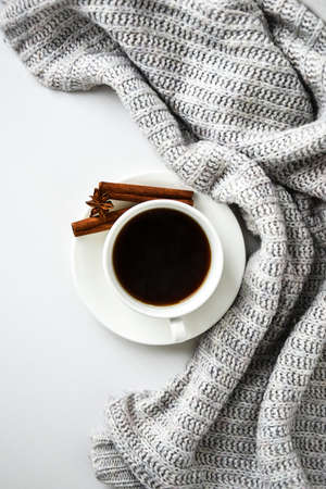 Cup of coffee with cinnamon sticks and anise star on white background. Sweater around. Winter morning routine. Coffee break. Copy space. Top view. Breakfast. Flat layの写真素材