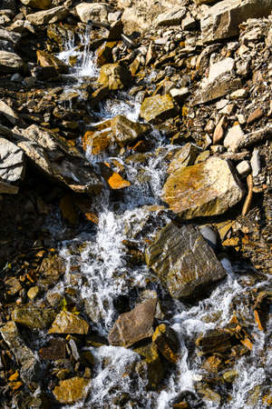 Big and small stones near the stream. The mountains. The texture of the stone. Background. Water falls on the rocks. Beauty in natureの写真素材