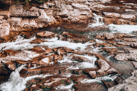 Big and small stones near the stream. The mountains. The texture of the stone. Background. Water falls on the rocks. Beauty in natureの写真素材