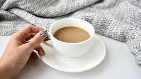 Hand in sweater with zebra animal printed nails with cup of coffee. Female manicure. Glamorous beautiful manicure. Manicure salon concept. Nail polish close up.の写真素材