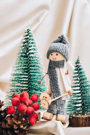 Christmas composition with doll skiing and fir trees festive decorations on silk. Christmas or New Year greeting card. Copy space. Trendy champagne colorの写真素材