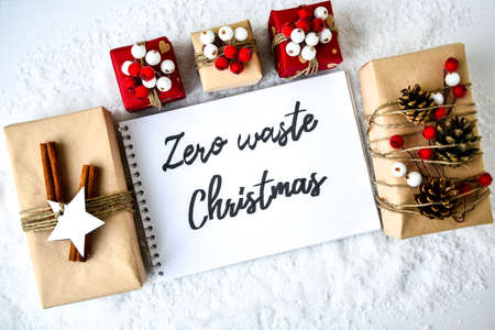 Zero waste Christmas text with presents with decorations on white snow background. Copy space. Eco friendly packed gift with tags from craft cardboard. New yearの写真素材