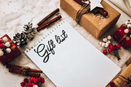 Notebook with GIFT LIST text Zero waste Christmas text with presents with decorations on white snow...