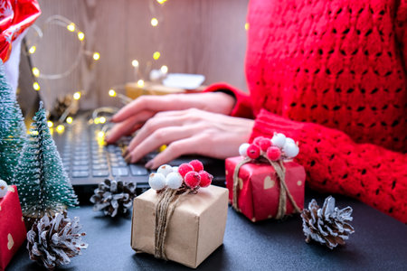 Christmas online shopping, work and education. New Year decorations on table. Woman with notebook...