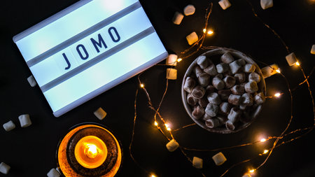 Lightbox with text JOMO Joy of Missing Out. The concept of relaxation from information and gadgets....