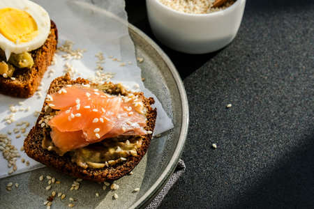 Toasted breads with poached eggs, avocado and salmon. Guacamole sandwiches. Healthy breakfast. Olive oil. Sesame seeds. Vegetarian healthy eating. Diet. Snack Selective focus, close upの写真素材