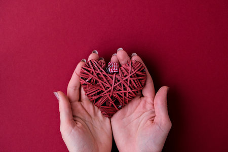 Female hands hold heart on red background. Valentines day. Holiday background with copy space. Card for love. New Year's Decorationの写真素材