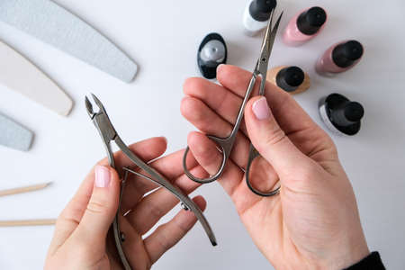 Woman hands, nail polish, manicure tools table top view flat lay. How to do manicure at home concept. Do manicure by yourself staying at home. Self care. Nude nails. Spa, medicine advertisement. Beauty.の写真素材