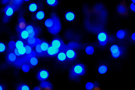 Defocused blue bokeh light of christmas tree at night. Blue bokeh background. Festive colorful backdropの写真素材