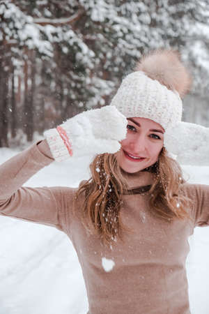 Christmas, holidays and season concept. Young happy woman blowing snow in the winter forest nature....