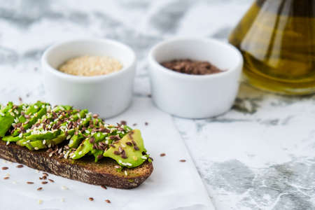 Healthy avocado toast on concrete background. Wholegrain bread, sesame flax seeds olive oil. Vegan...