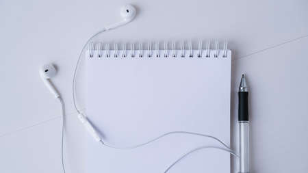 Open blank notebook with headphones and black pen. Copy space foe text. Top view. Pastel colorsの写真素材