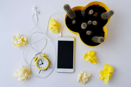 Creative work place with mobile phone headphones notebook with copy space, alarm clock and cactus. Work from home concept. Online education. Top view. Flat lay.の写真素材