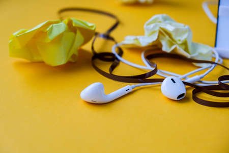 Hedphones with audio cassette tape and crumpled paper on yellow background, Copy space. Podcast episode. Audiobooks.の写真素材