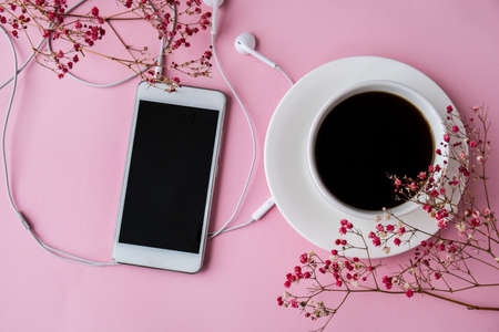 Open blank notebook with headphones mobile phone. Black coffee and screen. Dry pink flowers decoration. Workplace. Copy space for text. Top view. Pastel colorsの写真素材