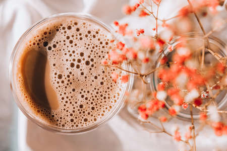 Cup of latte cappuccino. Morning coffee aesthetics vibes. Breakfast. Pink gypsophila flowers Hard shadows. Delicate lightの写真素材