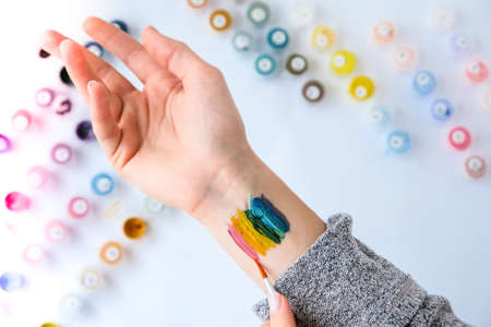 Rainbow LGBTQ flag painted on hand. Support for lgbt community. Honor of pride month. Connecting people, touching hands. Multi colored hands art creativity, discrimination.の写真素材