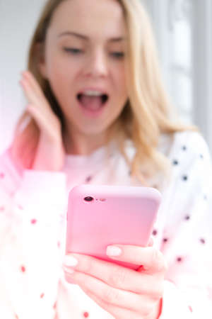 Blonde young girl taking selfie. Video call. Online education. Work from home. Woman holding smartphone. Phone call. Recording new vlog for her channel. Blogger Conference surprisedの写真素材