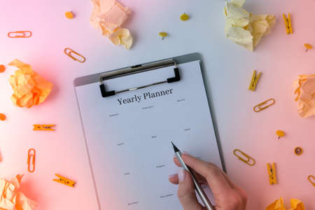 Yearly goals planner on white background. Planning year to stay productive when working from home during quarantine period. Flat lay. Top view. Alarm clock penの写真素材