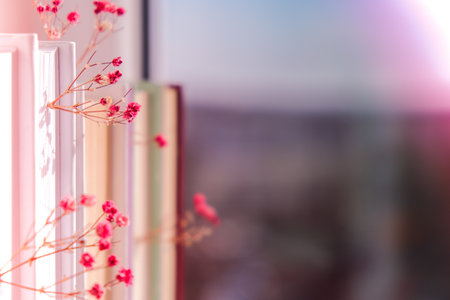 Stack of old books with babys breath flowers. Cozy reading. Delicate pink gypsophila flowers. Slow living concept. Unity with nature. Education literature. Selective focus.の写真素材