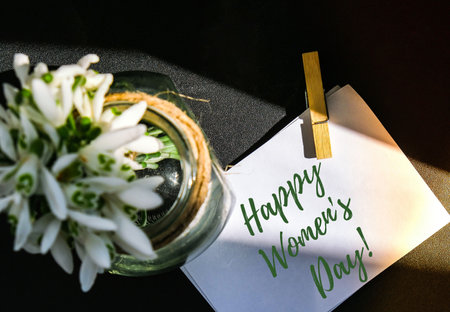 Happy Womens Day lettering greeting card. Spring flowers snowdrop. Beautiful tender bouquet of flowers. Holiday concept. Creative modernの写真素材