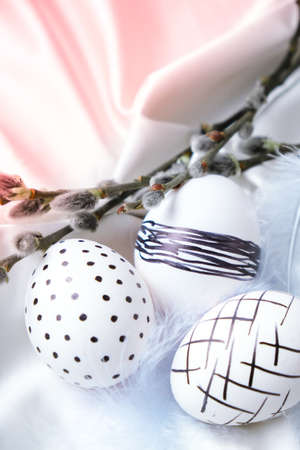 Trendy colored stylish Natural easter eggs, feathers, pussy willow branches on rustic cloth on white...
