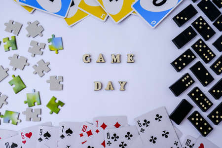 Kiev, Ukraine - 10.03.2021 Text GAME DAY. Dominoes puzzles playing cards around. The concept of relaxation from information and gadgets. Top view, flat lay. Board games. Table game. Pastimeのeditorial素材