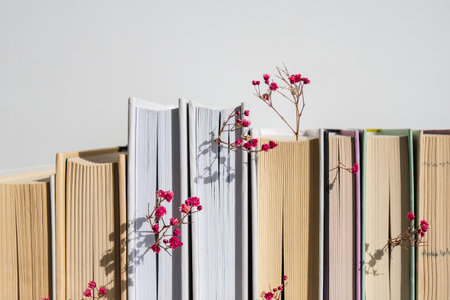 Stack of old books with babys breath flowers. Cozy reading. Delicate pink gypsophila flowers. Slow living concept. Unity with nature. Education literature. Selective focus.の写真素材