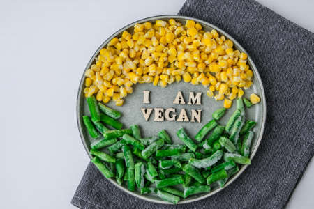 I AM VEGAN text in plate. Veganism, vegetarian healthy lifestyle green beans yellow corn. Healthy eating vegan. Wooden lettersの写真素材
