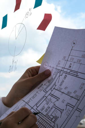 Female interior designer drawing house plan in office. Workplace Workspace window. Architect at work. Architectural building design and construction plans with blueprintsの写真素材