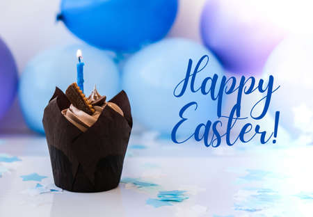 Happy Easter day text greeting card. Chocolate cupcake with candle. Holiday. Celebration background.