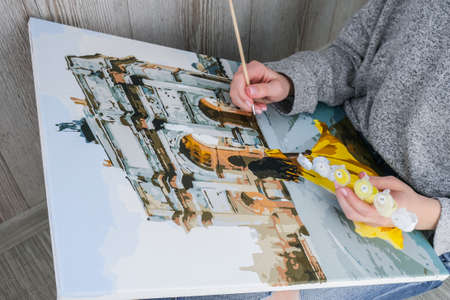 Female hands coloring canvas Picture by numbers girl Triumphal Arch Paris. Creative hobby. Painting...
