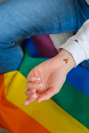 Closeup of young caucasian millennial hippie woman with painted rainbow flag in heart shape painted...