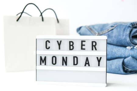 Light board with text CYBER MONDAY with paper shopping bags, jeans clothes. Big Sale online shopping concept. Promotion advertising. Holidayの写真素材