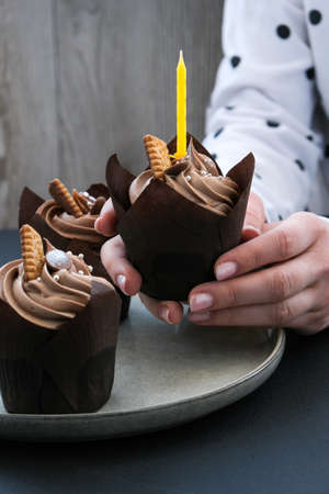 Female hands making Delicious chocolate cupcakes with cream on dark background. Three chocolate muffin. Birthday cake party preparation. Homemade Chocolate Cupcakeの写真素材