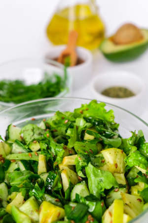 Salad of fresh green vegetables and herbs. Cooking healthy diet or vegetarian food. Step by step recipe. Healthy eating. Ingredients for salad. Raw food concept. A variety of organic fruits and vegetables with avocado. Vegan menu. Fresh spinach and green onion leaves, arugula. Flax seedsの写真素材