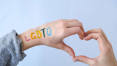 Rainbow LGBTQ flag painted on hand. Support for lgbt community. Honor of pride month. Connecting people, touching hands. Multi colored hands art creativity, discrimination. Heart shapeの写真素材