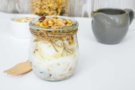 Healthy breakfast. Oatmeal Granola with greek yogurt and nuts banana muesli in jars on light background. Vegan, vegetarian and weight loss diet concept. Detox menu.の写真素材