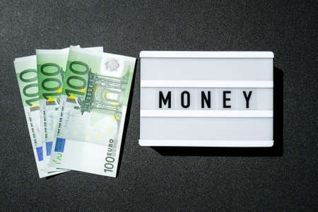 Lightbox board with the word MONEY in black letters around Euro banknotes. Finance background....