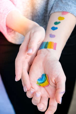 Rainbow LGBTQ flag painted on hand. Support for lgbt community. Honour of pride month. Connecting people, touching hands. Selective focusの写真素材