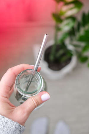 Top view female hand drinking water from eco bottle with metal reusable straw tube. Mindfulness meditation. The concept of healthy nutrition, environmental friendliness and zero waste. Self-isolation is beneficialの写真素材