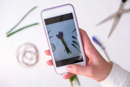 Female hands take photo of bouquet blue muscari as a gift. Pruning flowers. Blogger, influencer Florist in flower shop. Eco-style. Florist at work workspace. Woman making bouquetの写真素材