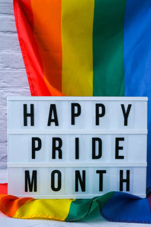 Rainbow flag with lightbox and text HAPPY PRIDE MONTH. Rainbow lgbtq flag made from silk material. Symbol of LGBTQ pride month. Equal rights. Peace and freedomの写真素材
