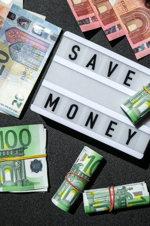 Lightbox board with word SAVE MONEY in black letters around euro banknotes.の写真素材